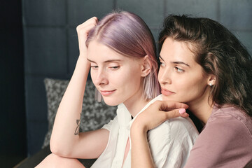 Attractive young Caucasian woman listening to girlfriend while they sitting on bed