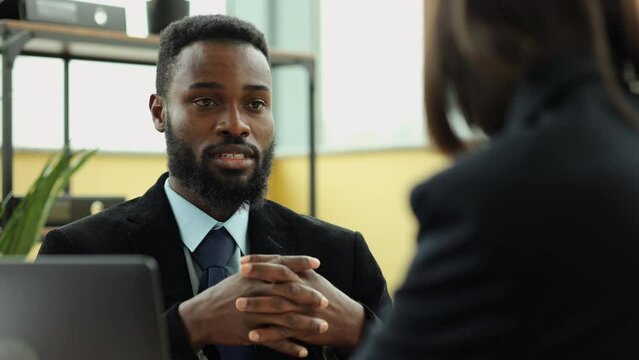 Closeup view of man, woman analysts talking and sitting at table in company during working day spbi. 4k video African American guy speaks to female and looks with smile, discusses project and sits at