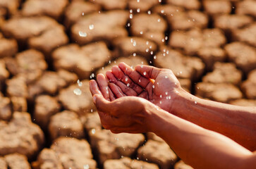 hands washing with water pouring from a tap on dry ground.