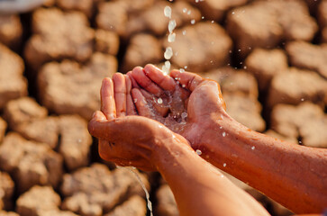hands washing with water pouring from a tap on dry ground.