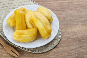 Fresh and ripe jackfruit served on a plate on a wooden table. Space for text.

