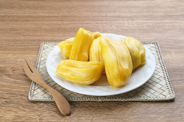 Fresh and ripe jackfruit served on a plate on a wooden table. Space for text.
