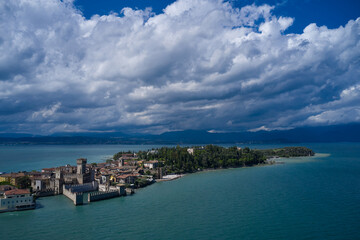 Naklejka na ściany i meble Rocca Scaligera Castle in Sirmione. Aerial view on Sirmione sul Garda. Italy, Lombardy. Cumulus clouds over the island of Sirmione. Panoramic view at high altitude. Aerial photography with drone.