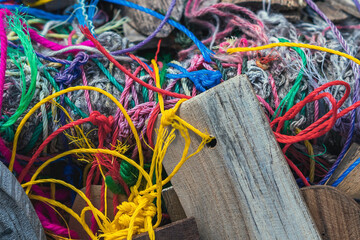 Many suspended chaotically intertwined colorful ropes tied into messy knots for plate wood hanging...