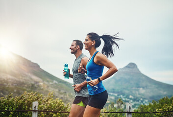 We compete in a friendly way. Shot of a young attractive couple training for a marathon outdoors.