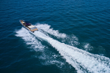 Boat drone view. Speedboat moving fast on blue water aerial view. Dark gray blue boat in motion at sea.