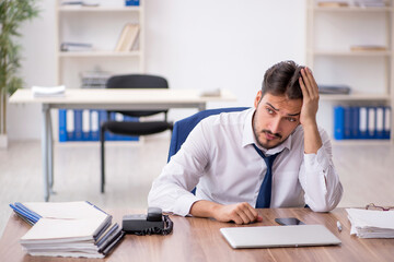 Young male employee unhappy with excessive work in the office
