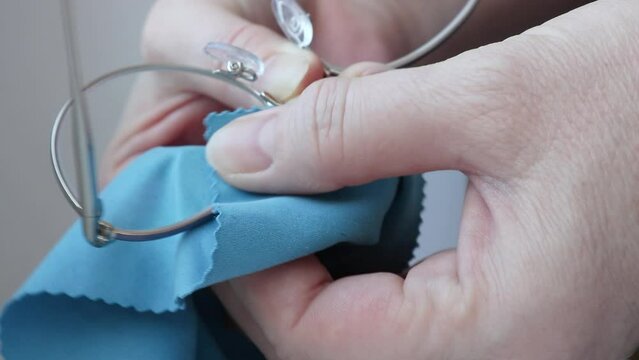 Close-up of hands cleaning diopter glasses with a microfiber cloth. Selective focus.
