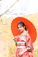 Asian tourists wearing Japanese national costumes holding red umbrellas