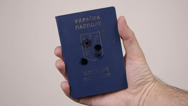 War between Russia and Ukraine. The concept of murder, occupation, aggression. Male hand holds a blue passport of Ukraine.