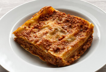 Italian meat Lasagne in a white dish on wooden background. Portion of traditional Lasagna on a plate. Close-up