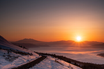 眩しい朝陽が雪の斜面を照らす峠の夜明け。日本の北海道の美幌峠で。