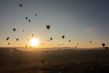 Hot air balloons in the sky during sunrise. Flying over the valley at Cappadocia, Anatolia, Turkey. Volcanic mountains in Goreme national park.