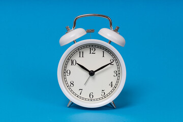 Retro alarm clock on blue background. Old fashioned alarm clock