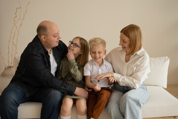 Mom, Dad, son and daughter spend time together. Portrait of a family in the fourth, in the interior. The relationship of children and their parents.