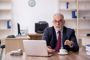 Old male employee drinking coffee during break