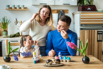 the family paints colorful Easter eggs. mom, dad and daughter celebrate spring holiday together