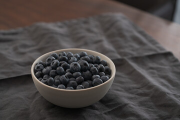 Fototapeta na wymiar Blueberries in ceramic bowl on wood table