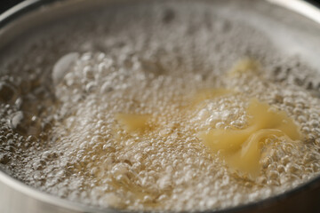 Farfalle pasta in hot boiling water in saucepan closeup