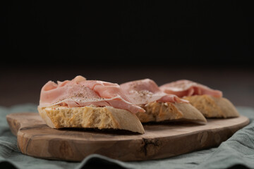 Toassted baguette slices with prosciutto cotto and cream cheese on olive wood board