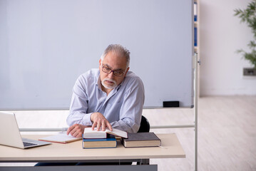 Old male teacher in front of whiteboard