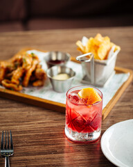 Refreshing red cocktail with blurred snack set on the background