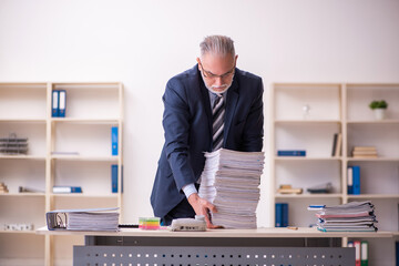 Old businessman employee unhappy with excessive work in the office