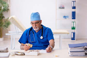 Old male doctor working in the clinic