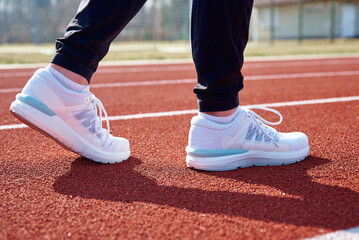 Fototapeta na wymiar Male runner feet with white sneakers at stadium track, close up. Sport sneakers for jogging. Fitness and healthy lifestyle concept