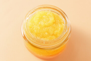 Sugar peeling for the body of orange color on a plain background, top view. Cosmetic product for skin care.