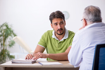 Young man visiting old male doctor