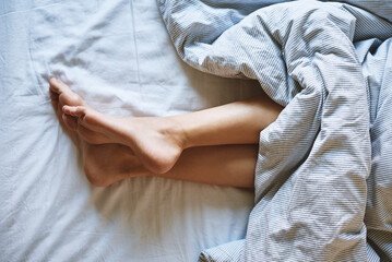 Morning concept, Woman sleeping in bed, Naked female legs under blanket