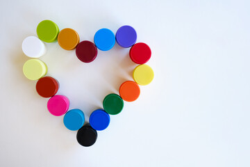 Jars with multi-colored paints in the shape of a heart. Creative background. Paint for drawing. Love postcard. Mock up