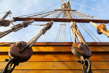 Part of an old sailing wooden ship with a rope ladder with pulleys, knotted ropes and wooden...