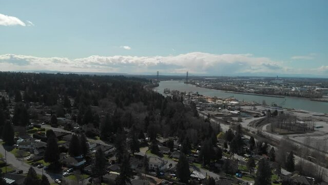 Scenic view of Delta BC on the edge of the Fraser river with the Alex Fraser bridge in the background Bright day blue sky clouds Aerial Wide approaching from high above