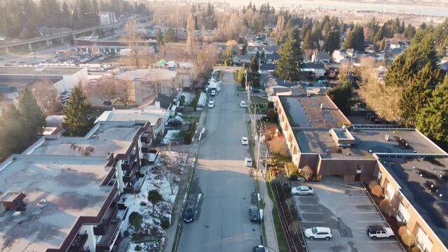 Whalley neighbourhood Surrey BC Aerial wide moving forward looking down panning up to reveal condo buildings apartments along road leading to scenic view of Fraser River