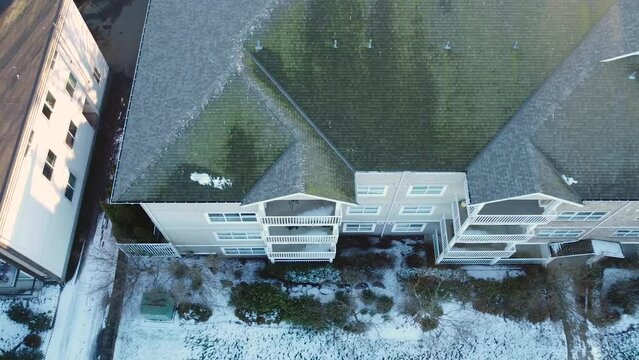 the roof of 4 story condo building covered in green moss and algae in Whalley Surrey BC city neighbourhood Aerial top down trucking right