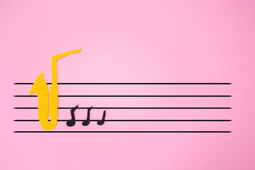 International Jazz Day. Silhouette of a saxophone cutted out of felt with notes, on a pink...