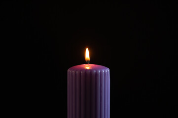 Purple candle with orange flame over black background