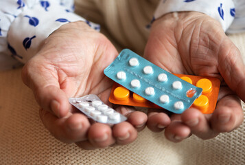 An old woman holds pills in her hands. Selective focus.