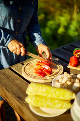 Unrecognizable woman cutting fresh pepper vegetables on wooden board