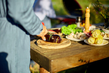 Unrecognizable woman cutting fresh eggplant vegetables on wooden board