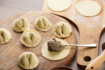 Process of preparation of traditional ukrainian east european dish varenyky - dumplings stuffed with potato-mushroom paste. Wooden background