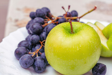 Fruit and berry mix with green apple and black grapes on a plate