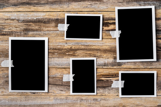 Paper blank photo frames hanging on wooden wall