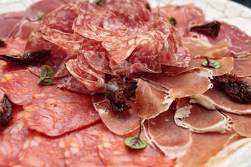 Sliced meat on a white plate, on a dark background