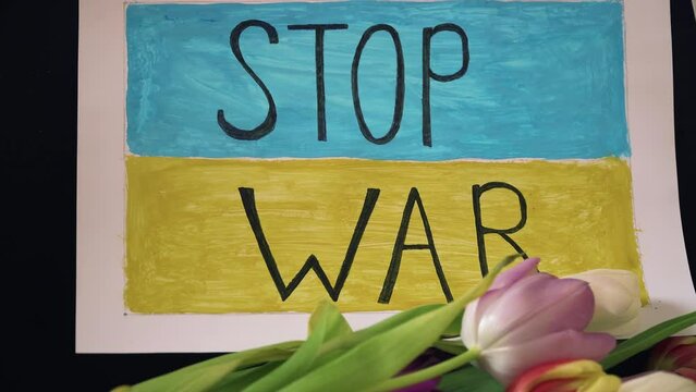 Inscription Stop war on motivational packard against armored conflict on background of Ukrainian flag with flowers. Crisis, peace, stop aggression in whole world