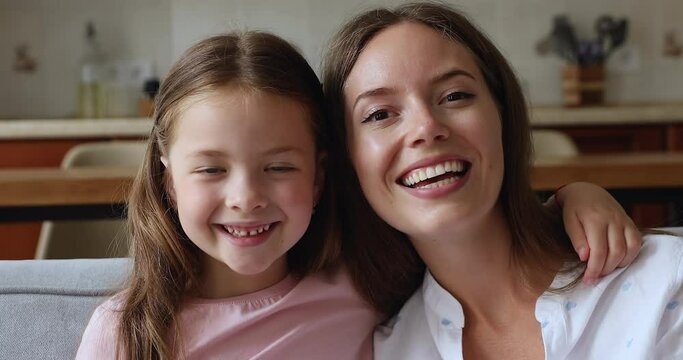 Close up portrait little daughter hug young beautiful mother look at camera having wide toothy perfect smile advertise dental services clinic. Happy motherhood, family ties, unconditional love concept