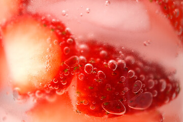 Sliced strawberries, ice cubes, cold water, water bubbles, condensation on glass