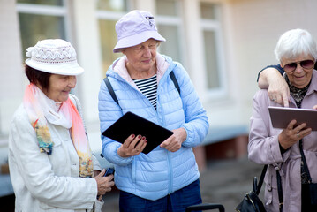 Obraz premium A group of happy elderly tourists using tablet